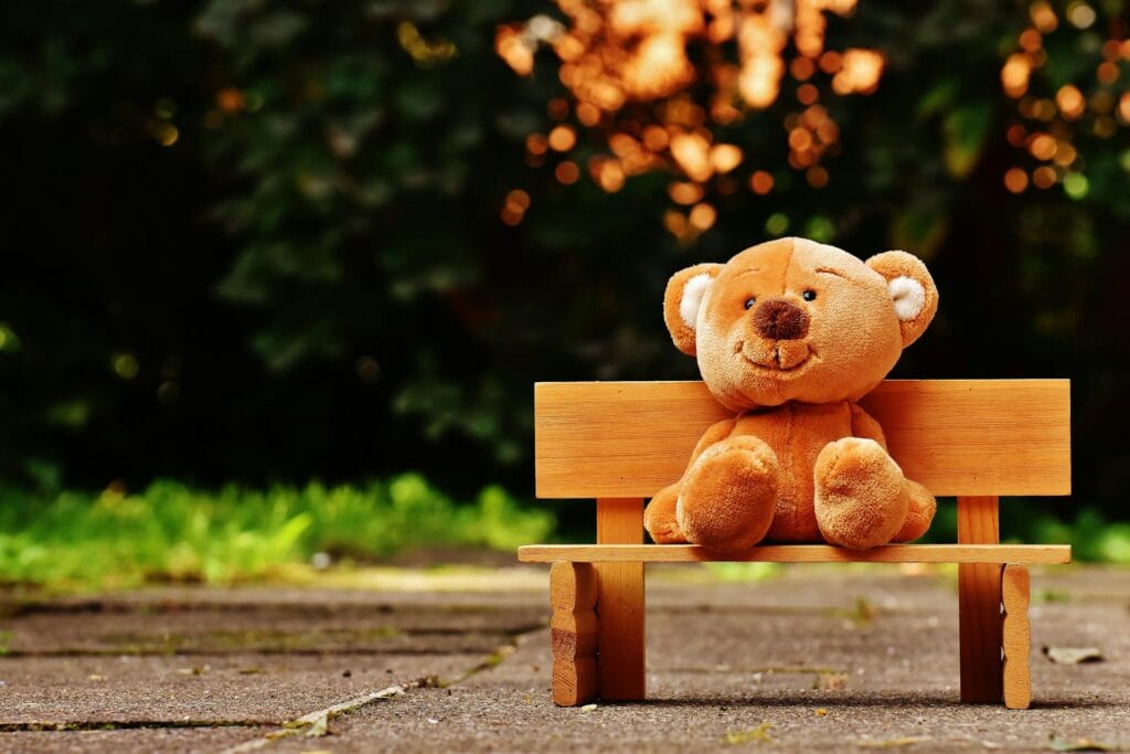 Teddybär sitzt auf einer Bank.